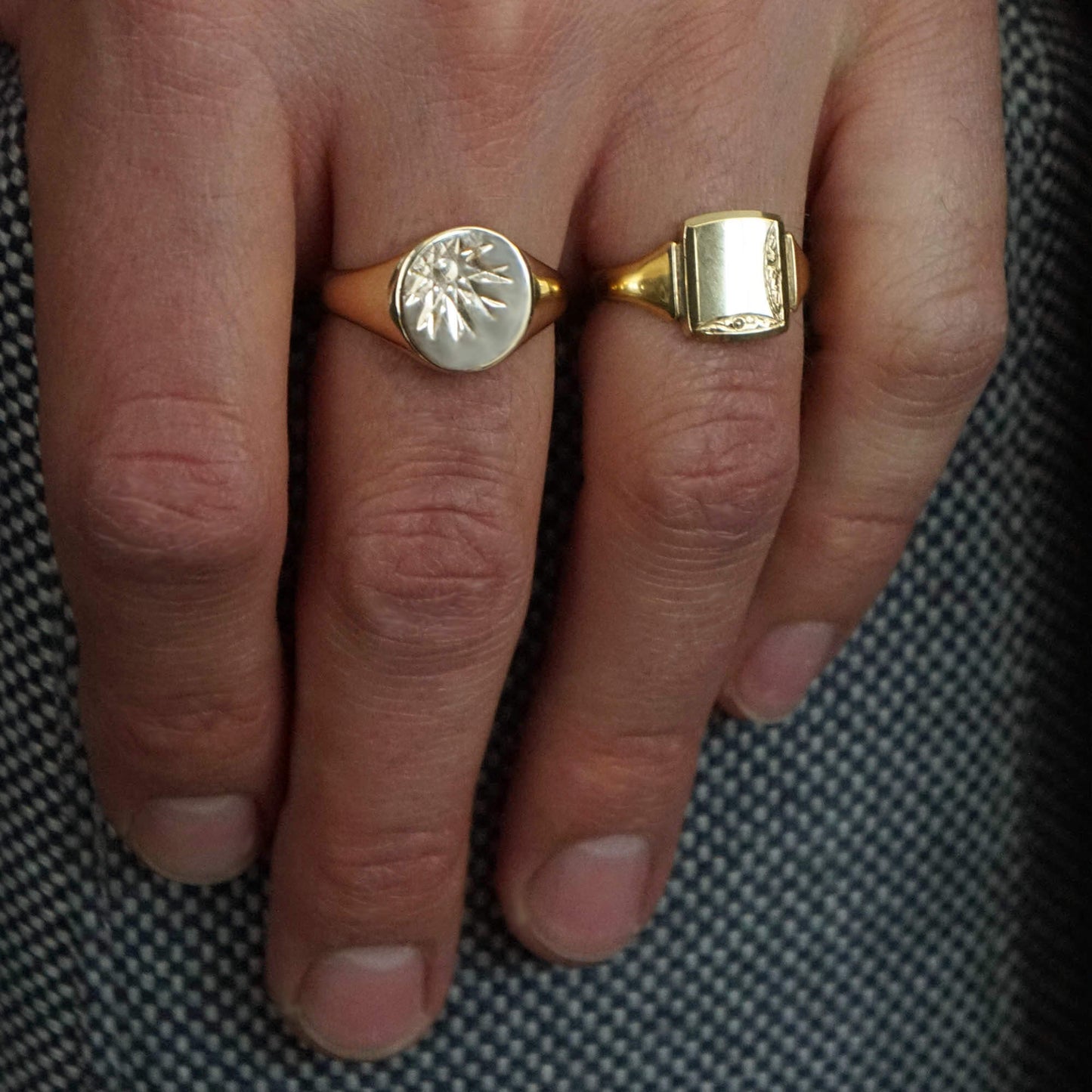 Close up mans hand wearing Vintage 9K gold 70s sunburst ring on middle finger, and vintage patterned ring on wedding finger.