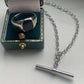 SILVER & BLACK ONYX CUSHION SIGNET RING IN DARK GREEN JEWELLERY BOX, STYLED NEXT TO SILVER T BAR CHAIN NECKLACE.