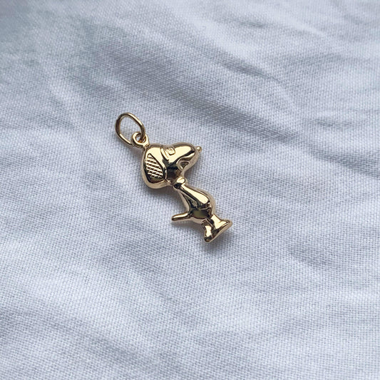 9k gold snoopy charm pendant styled on a white textured background
