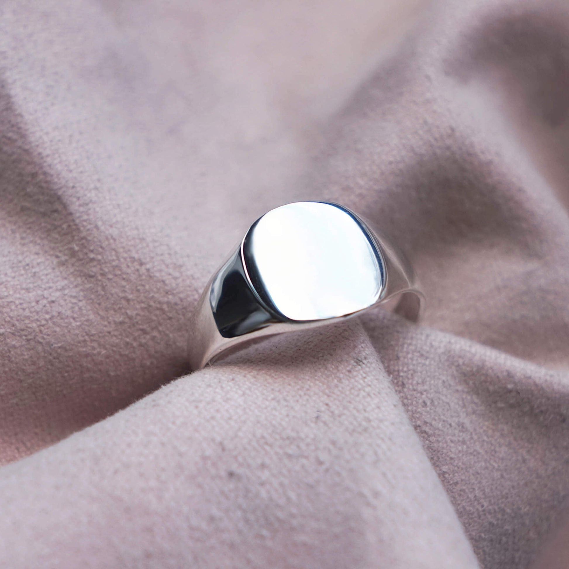 STERLING SILVER CUSHION SMOOTH SIGNET RING IN A PINK JEWELLERY CLOTH.