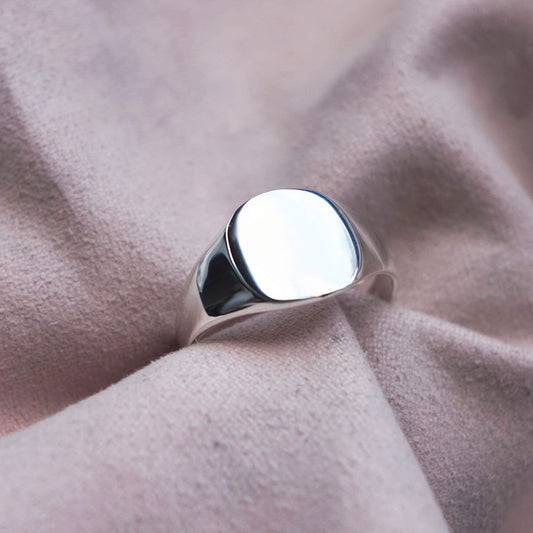 STERLING SILVER CUSHION SMOOTH SIGNET RING IN A PINK JEWELLERY CLOTH.