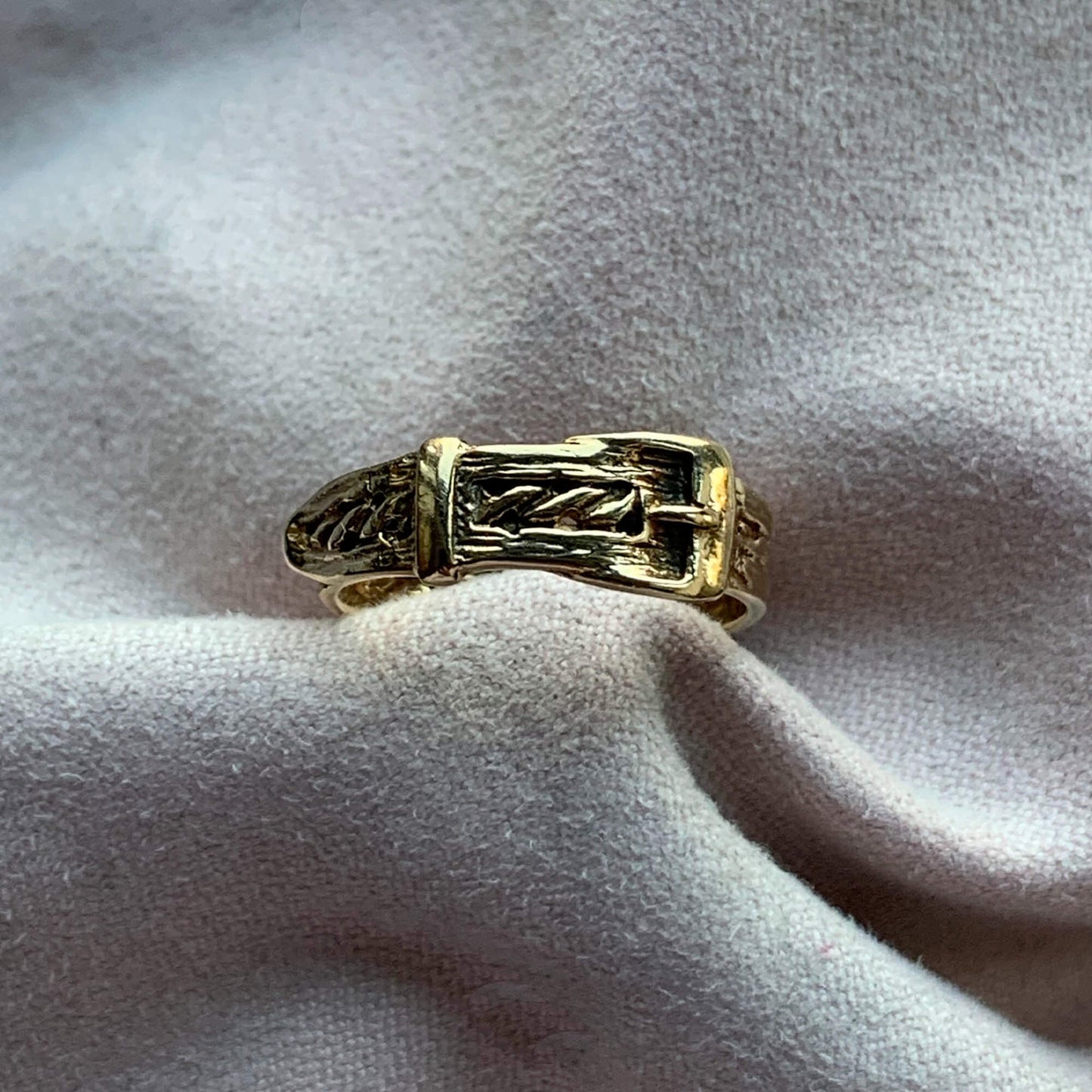 Vintage 9K gold buckle ring with braid detail, nestled in pink jewellery cloth.