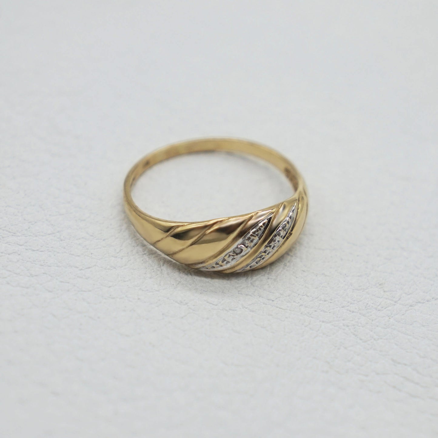 side profile fine 9k gold vintage diamond croissant style ring on white textured background.